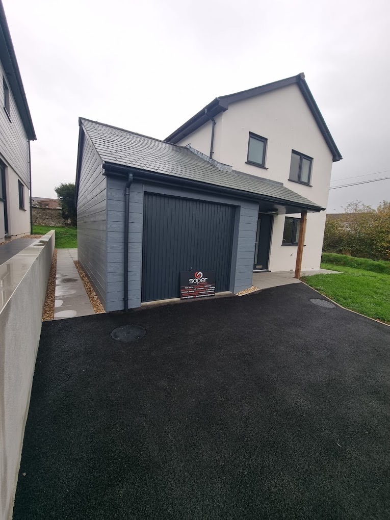 Newly converted garage with dark cladding and tarmac driveway