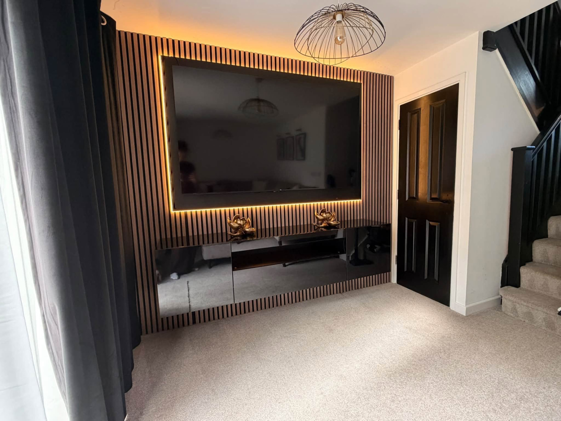 Oak slat media wall with floating black cabinet and TV halo lighting